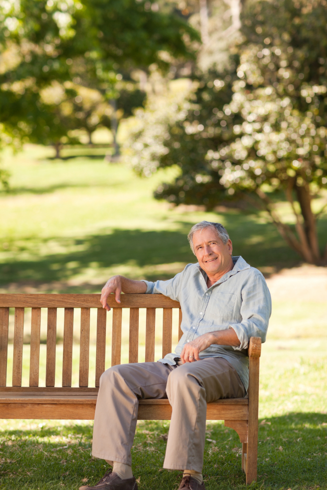 Senior man sitting on a park bench in the sunshine